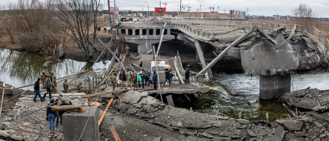 IRPIN, UKRAINE - Mar. 05, 2022: War in Ukraine. People cross a destroyed bridge as they evacuate the city of Irpin, northwest of Kyiv, during heavy shelling and bombing