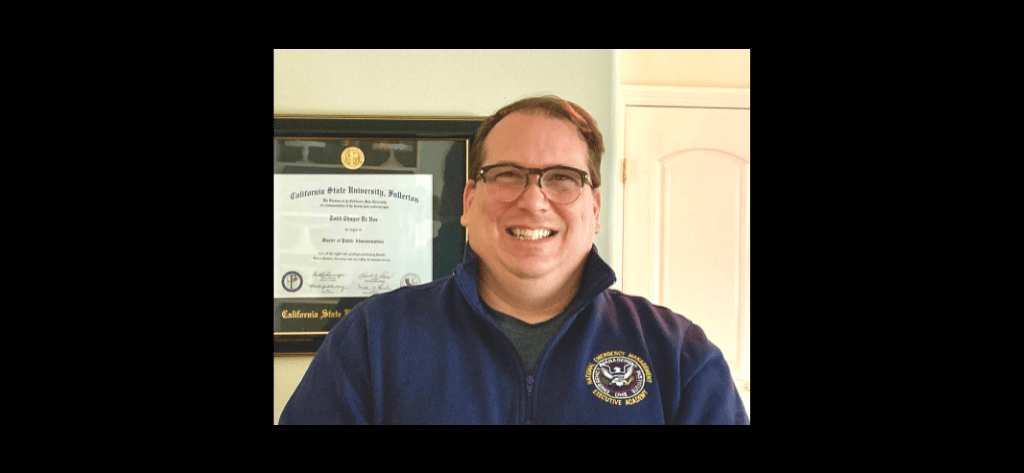 Todd DeVoe emergency management coach in his office by his masters degree